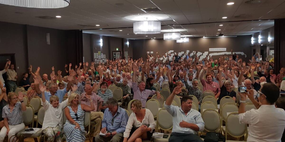More than 400 people raise their hand at Coonamble Bowls Club as an indication coal seam gas mining should not be allowed in NSW.