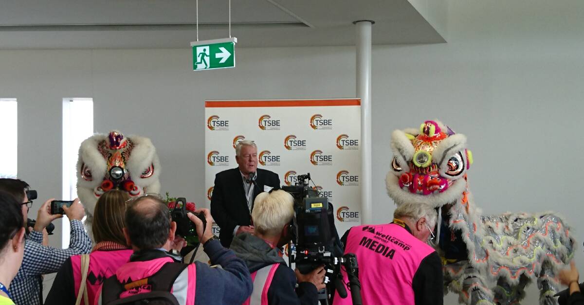 History in the making: John Wagner, flanked by Chinese dragons addresses the media prior to the departure of the first international passenger flight out of Wellcamp. Picture: Sally Cripps.