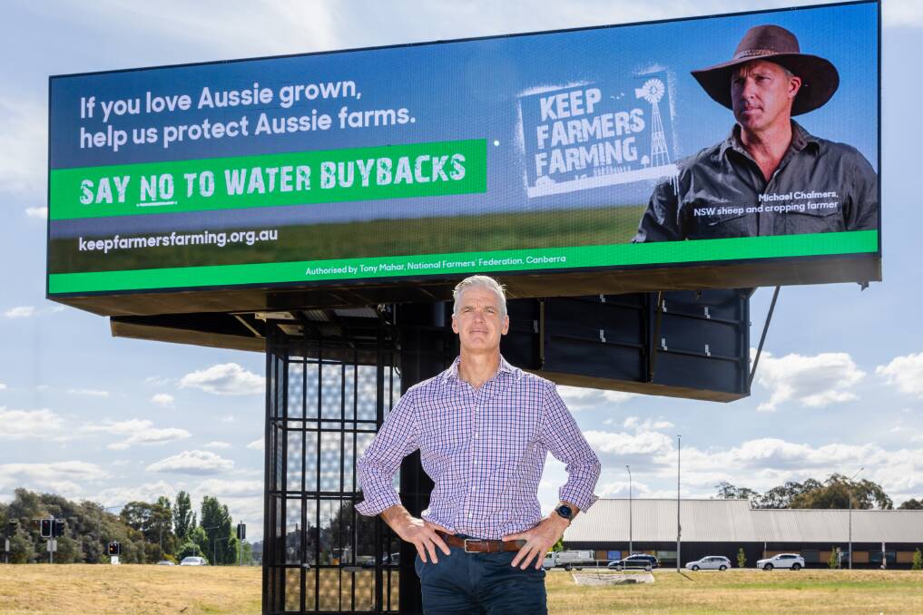 National Farmers' Federation chief executive Tony Mahar in front of the campaign billboard in Canberra, which features sheep and grain farmer Michael Chalmers.