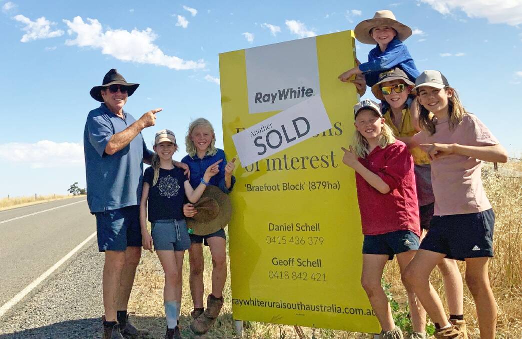 Ray White principal Geoff Schell puts up the sold sticker on the Booborowie/Leighton aggregation with the help of his grandchildren. Pictures from Ray White