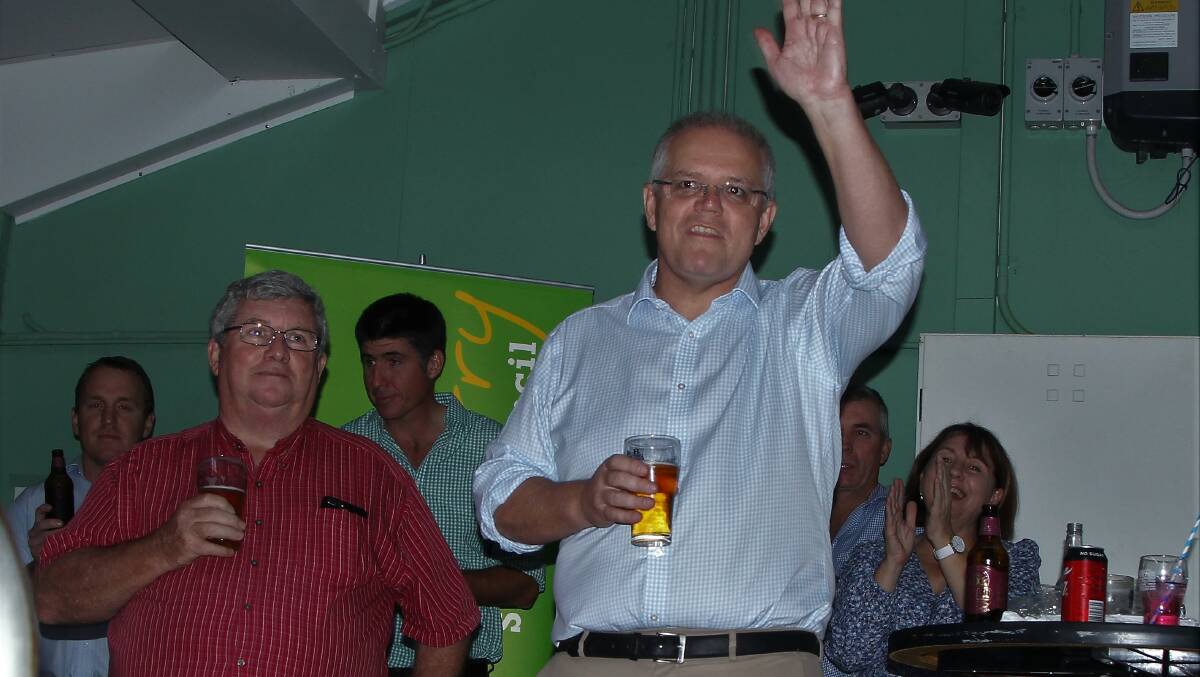 Prime Minister Scott Morrison salutes the crowd gathered at the Cloncurry Bowls Club, alongside North Queensland Livestock Industry Recovery Agency chairman Shane Stone.