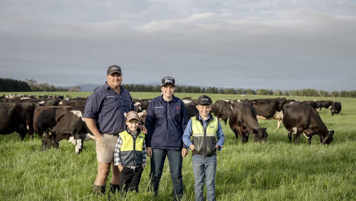 Woodrising Dairies farm manager Troy Ainslie with his children Albie, Indianna and Archie in a paddock where cows are grazing inside a virtual fence. Picture by Oscar Sloane