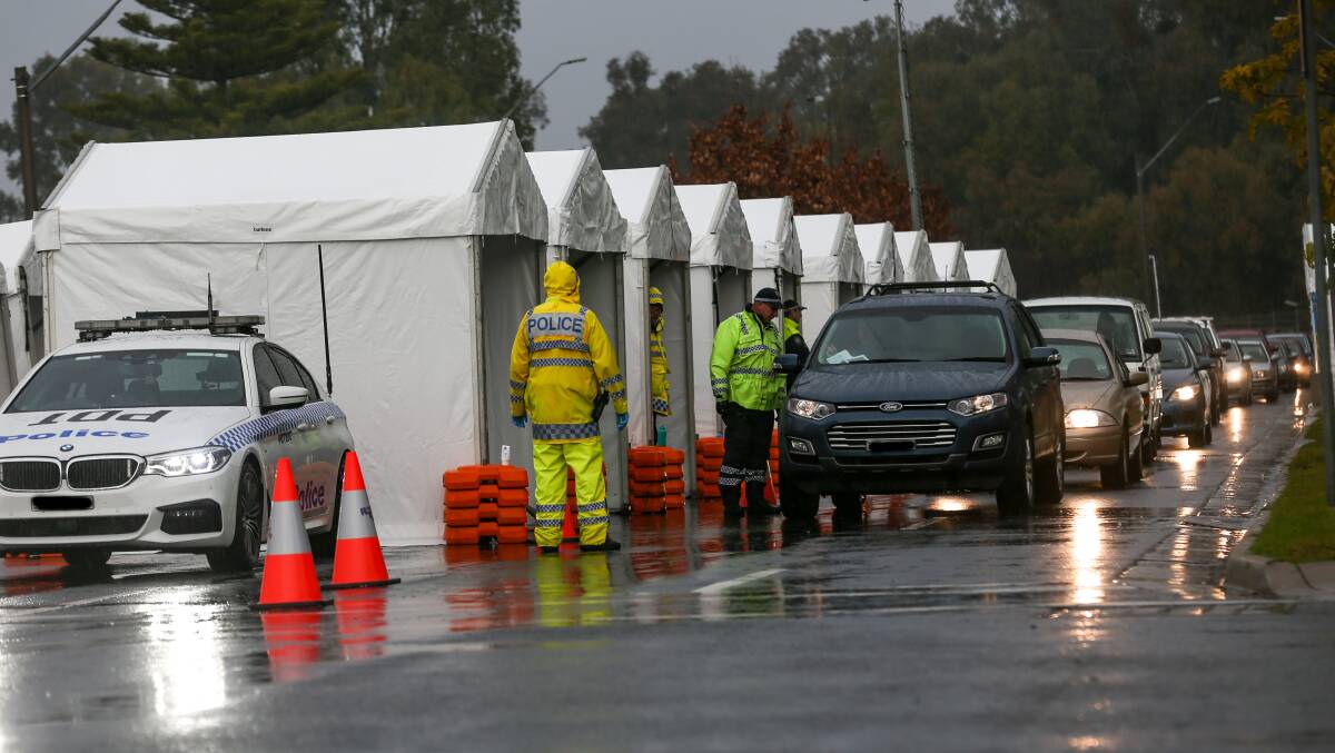 GLOOMY QUEUE: Police stop a line of cars entering NSW at Albury's Wodonga Place amid rainy conditions on Sunday morning. Picture: TARA TREWHELLA